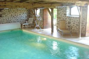 a swimming pool in a house with two chairs at Gite linstant rêvé in Labesserette