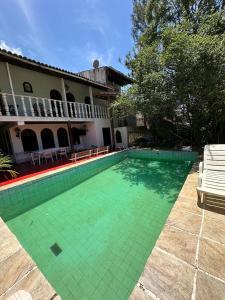 a swimming pool with green tile in front of a house at Pousada Dodô in Itaguaí