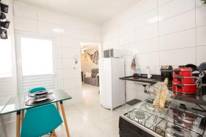 a white kitchen with a refrigerator and a table at Jahu Center Casas Un 2 in Jaú