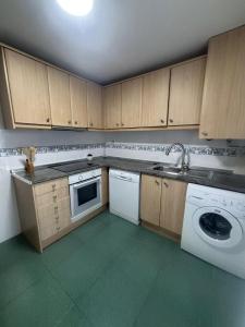 a kitchen with wooden cabinets and a white dishwasher at ElFogaril in Teruel