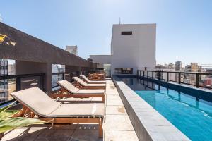 a pool on the roof of a building with lounge chairs at Studio with Pool and Gym - DP203 in São Paulo