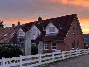 a red brick house with a white fence at Landhaus Behrenwalde in Weitenhagen