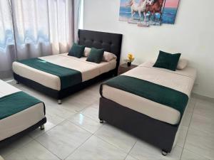 a bedroom with two beds and a painting on the wall at Cartagena Sotavento Laguito in Cartagena de Indias
