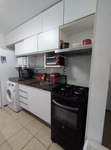 a kitchen with white cabinets and a black stove at AV80101 - Aquaville Térreo - Porto das Dunas - CEARÁ in Aquiraz