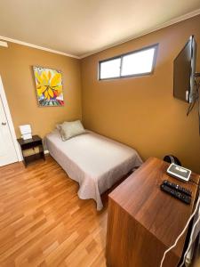 a bedroom with a bed and a desk and a television at Hotel Boutique Casa Piedra in Tocopilla