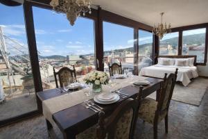 a dining room with a table and a bed and windows at Royal stylish view apartment in Koropi