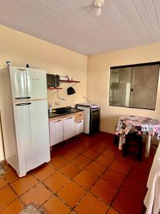 a kitchen with a white refrigerator and a table at Casa Beira Mar in Matinhos