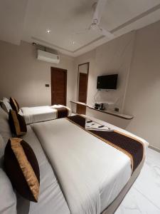 two beds in a hotel room with a tv on the wall at Hotel Liora Suites in Bangalore