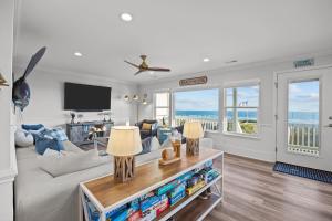 a living room with a couch and a tv at Oceanfront luxury, private pool & beach access! in Holden Beach