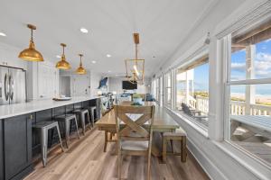 a kitchen with a table and chairs and windows at Oceanfront luxury, private pool & beach access! in Holden Beach