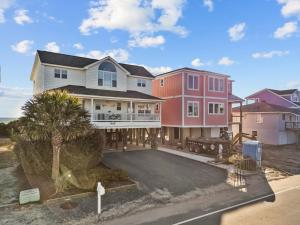 a large house with a driveway in front of it at Oceanfront luxury, private pool & beach access! in Holden Beach