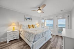a white bedroom with a bed and a balcony at Oceanfront luxury, private pool & beach access! in Holden Beach +43 photos