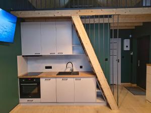 a loft kitchen with white cabinets and a sink at Cieniówka, dom w lesie, Kije in Kije +7 photos