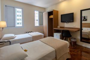 a hotel room with two beds and a flat screen tv at Hotel Amalia by Plaza Xavier in São Paulo
