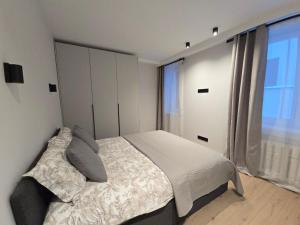 a bedroom with a bed and a large window at Haustory Deluxe Apartment in Klaipėda