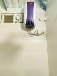a purple hair dryer on the wall of a bathroom at Thulir Farm Stay Near Isha Yoga Adiyogi in Coimbatore