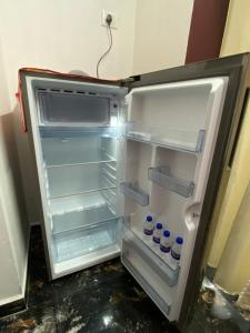 an empty refrigerator with its door open in a room at Thulir Farm Stay Near Isha Yoga Adiyogi in Coimbatore