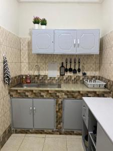 a kitchen with white cabinets and a sink at Résidence NECTAR 2 in Abidjan
