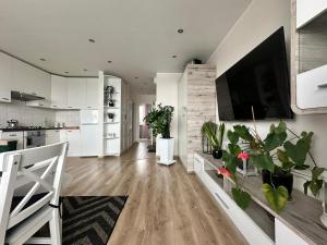 a kitchen and living room with white cabinets and a flat screen tv at Mazury Witaj in Ostróda