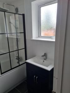 a bathroom with a sink and a shower with a window at 1 Bedroom Flat Ground Floor - Central Dunstable in Dunstable +3 photos