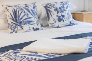 a white towel on a bed with blue and white pillows at La suite d'Amanda-wifi-jardin NO KITCHEN in Villefranche-de-Rouergue