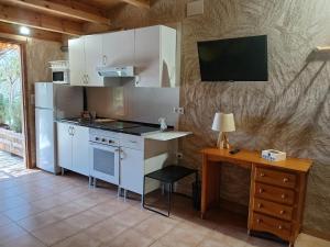 a kitchen with white cabinets and a table and a desk at Casita Sol in Villafamés