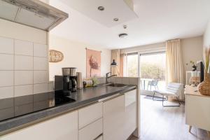 a kitchen with white cabinets and a black counter top at Appartement De Jutter, Resort Amelander Kaap in Hollum