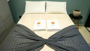 a bed with a blanket and two books on it at Jahu Center Casas Un 3 in Jaú