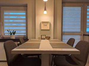 a dining room with a table and chairs and windows at Silver Apartament Kowary in Kowary +3 photos