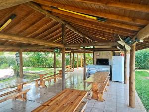 a pavilion with wooden benches and a refrigerator at Park Golf Hostel Ipelandia in Foz do Iguaçu