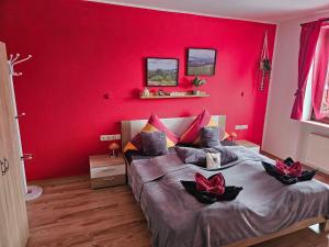 a red bedroom with a bed with two flowers on it at Pension Heuhexe in Fladungen