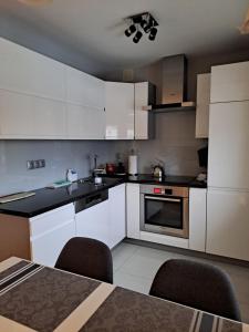 a kitchen with white cabinets and a table and chairs at Silver Apartament Kowary in Kowary