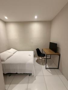 a bedroom with a bed and a desk with a laptop at Pousada Meu Aconchego in Fortaleza
