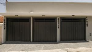 a pair of garage doors on a building at Jahu Center Casas Un 3 in Jaú