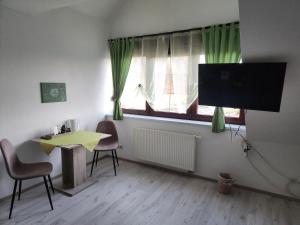 a living room with a table and a tv and a window at Pension Heuhexe in Fladungen