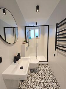 a white bathroom with a sink and a mirror at Haustory Deluxe Apartment in Klaipėda +14 photos
