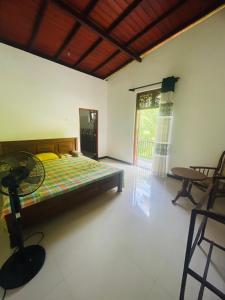 a bedroom with a bed and a table and a window at Iwasuma Homestay in Dickwella