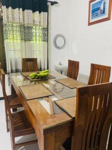 a dining room table with chairs and a wooden table with bananas on it at Iwasuma Homestay in Dickwella