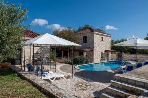 a pool with chairs and umbrellas next to a house at South Estate in Čilipi
