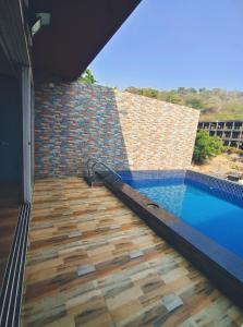 a swimming pool with a wooden floor and a brick wall at Villa 04 in Mumbai +3 photos
