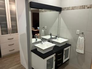 a bathroom with two sinks and a large mirror at Chasing Jacuzzi Sunsets sea and mountain views in Hermanus +19 photos