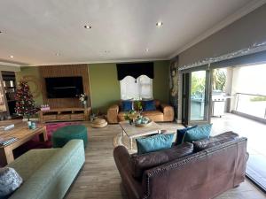 a living room with leather furniture and a christmas tree at Chasing Jacuzzi Sunsets sea and mountain views in Hermanus