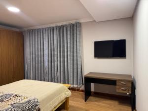 a bedroom with a bed and a desk and a television at Quarto para locação em apartamento in Conselheiro Lafaiete