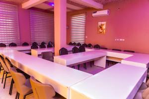 a room with white tables and chairs and pink walls at Grace villa in Zame