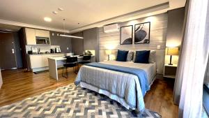 a bedroom with a bed and a desk and a kitchen at Hotel Flat Afonso Pena in Campo Grande
