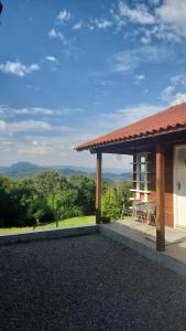 a house with a patio with a view of the mountains at Chalé Vale Carahá Hortensia in Gramado