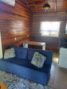 a blue couch in a living room with wooden walls at Chalé Vale Carahá Hortensia in Gramado