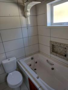 a bathroom with a toilet and a tub and a sink at Chalé Vale Carahá Hortensia in Gramado