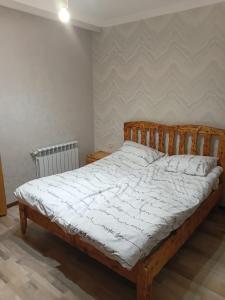 a bedroom with a wooden bed with white sheets at Villa Gast Haus in Tsaghkadzor