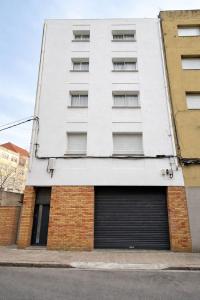 a white apartment building with a garage at Apartaments Montseny in Girona